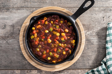 Mexican chilli beans with vegetables on wooden table. Top view