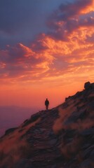 A solitary figure walks a mountain path at sunrise.
