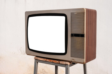 Side view, vintage old TV set on chair with blank white screen in front of white wall background.
