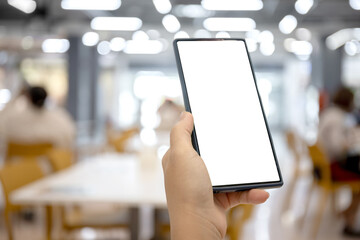 Smartphone with blank screen held in hand at food court, Restaurant in a shopping mall, Blurred background with people, Perfect for mobile app or banner website content placement