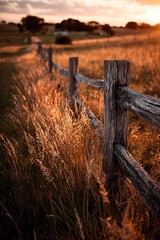 Rustic wooden fence bordering a field at sunset.