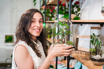 young woman portrait posing with a terrarium in her flower shop. concept of small business owner and woman entrepreneur