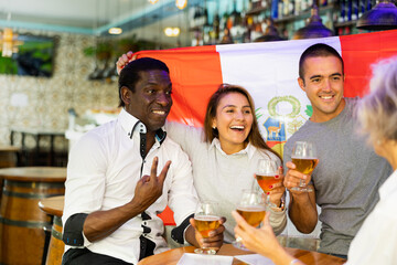 Happy friends celebrating the victory of the Peruvian team in a beer bar
