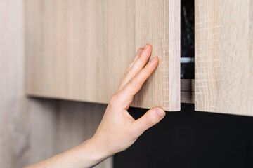 Person reaching for a modern kitchen cabinet in a stylish domestic space