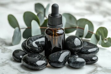 Dark amber dropper bottle nestled amongst smooth black stones and eucalyptus leaves on a white marble surface