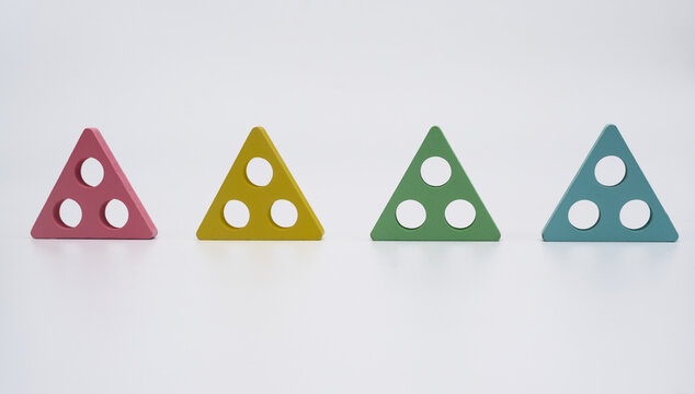 composition with vibrant triangle shapes symbolizing order and structure. Four colorful geometric triangle with circular holes placed in row on white background. 4 triangle shapes of different colors