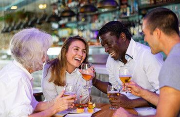 View on the happy diverse group laugh at a bar with beer