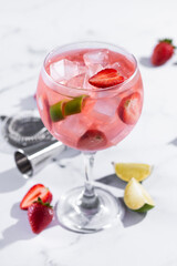 Strawberry gin tonic cocktail on white marble background