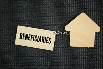 House shape and wooden tag with the word beneficiaries. a person who derives advantage from...