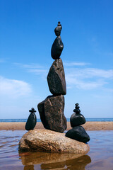 Rock zen pyramid of black stones on a background of blue sky