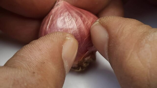 Macro footage of fingers peeling a shallot