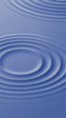 Concentric circular water ripples forming on a blue surface creating a calming wave like pattern vertically oriented