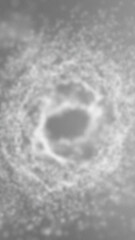 Blurred gray crater like depression surrounded by textured gray ground
