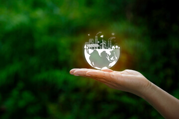 Hand holding digital earth with clean energy icons: solar, wind, factory, and trees. Concept of sustainable development, green technology, and environmental protection.