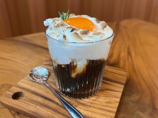 Black coffee with whipped egg white foam, finished with an egg yolk on top
