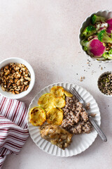 A nutritious, balanced breakfast featuring green buckwheat, fried hake, zucchini, and a fresh broccoli salad with pink radish, seeds, and nuts, offering a wholesome start to the day