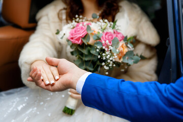 Close-up of groom helping bride step down, hands touching and bouquet in focus. Intimate wedding moment captured without showing faces. Symbol of support, love, and togetherness.