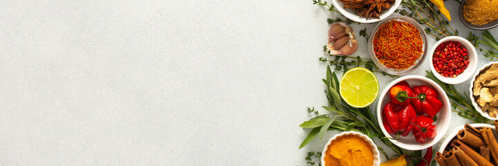 A mix of dried herbs and spices laid out on a gray background, highlighting natural flavors and...