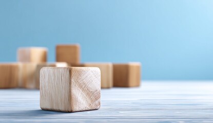 A perfectly crafted natural wooden block stands in sharp focus, symbolizing potential and a solid foundation on a blue table.