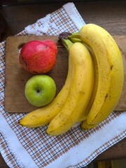 one green apple, one red pear and a bunch of bananas on a wooden board