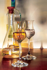 Two tulip glasses and bottle of liquor resting on wooden table