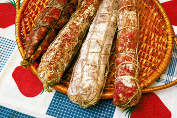 Seasoned sausages resting in a wicker basket on a checkered tablecloth