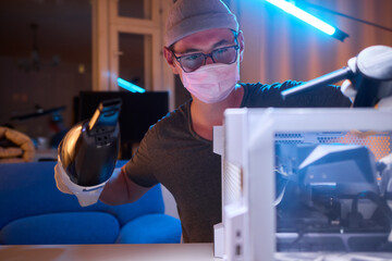 A man cleans a computer case with a vacuum in a bright room, stressing workspace tidiness