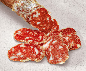 Sliced italian salami falling from a sausage on a kitchen top