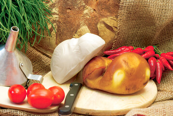 Smoked and fresh cheese with tomatoes, chili peppers and homemade bread on wooden cutting board