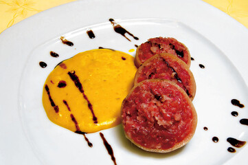 Slices of stuffed squid served with yellow sauce and balsamic vinegar cream