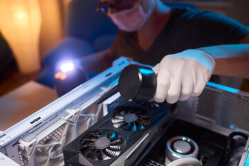 A man cleans a computer case with a vacuum in a bright room, stressing workspace tidiness