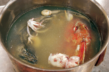 Chef preparing fish broth with squid, fish head and shrimp