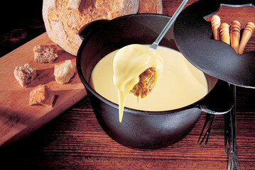 Dipping rye bread in cheese fondue using a long fork