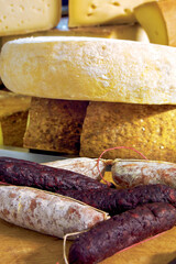 Displaying seasoned sausages and various cheese wheels in a delicatessen