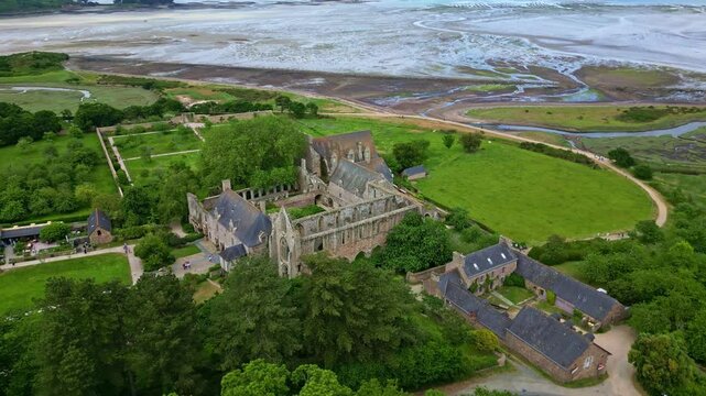 Sideways drone movement around the gothic Abbaye de Beauport historic abbey near tidal flats and countryside, Paimpol, Brittany, France.