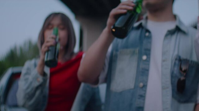 Young people engage in toast with bottles emphasizing commonness 