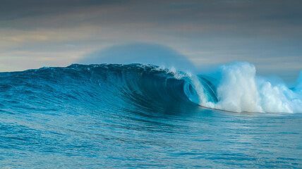 A dramatic photograph of a large ocean wave breaking in the open sea