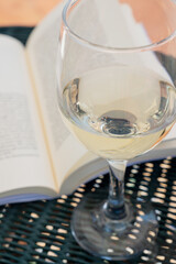 Close up of a glass of white wine with an open book in the background, a concept of relaxation