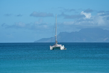 Beautiful beach of Beau Vallon, docking yacht, transparent and turquoise water, with silhouette...