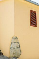 Facade of an old yellow building with decorative element and a small window