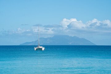 Beautiful beach of Beau Vallon, docking yacht, transparent and turquoise water, with silhouette...
