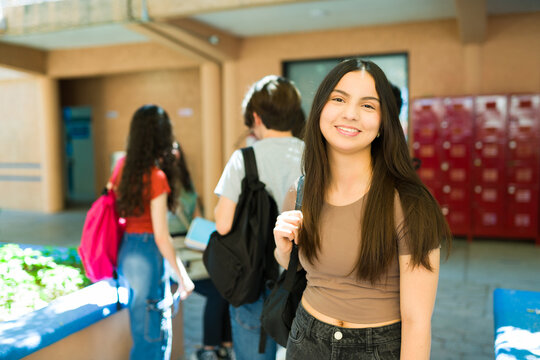 Fototapeta Portrait of smiling high school student girl with backpack in corridor