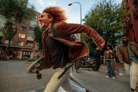 Young man running with skateboard in Madrid - Powered by Adobe