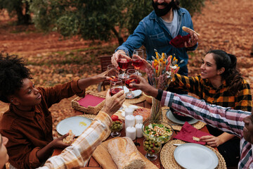 Friends toasting rose wine at outdoor picnic table