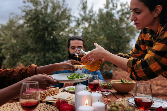 Farmers pouring olive oil on salad during open air meal in olive grove - Powered by Adobe