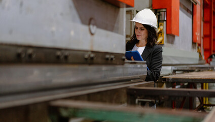 Woman engineer manager working at steel production factory. Female inspector wears safety hard hat...