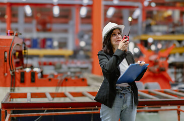 Woman engineer manager standing at steel production factory. Female inspector wears safety hard hat...
