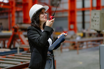 Woman engineer manager standing at steel production factory. Female inspector wears safety hard hat...