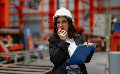 Woman engineer manager standing at steel production factory. Female inspector wears safety hard hat...