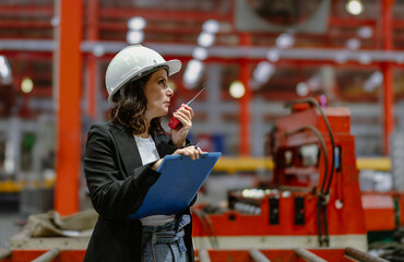 Woman engineer manager standing at steel production factory. Female inspector wears safety hard hat...